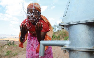 woman washes face with clean water from Rotary and WaterAid