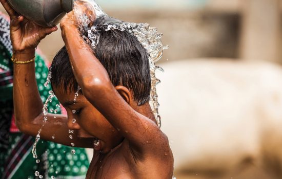 child washes using water from new pump supplied by One Drop charity