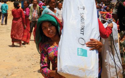 Woman carries disaster relief items supplied by charity ShelterBox