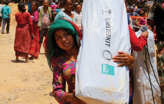 Woman carries disaster relief items supplied by charity ShelterBox