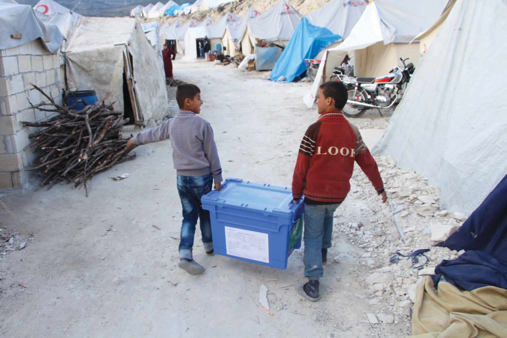 Two boys carry Aquabox in refugee camp