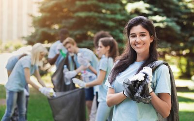 Volunteering and ecology concept. Happy woman with friends collecting recyclable litter in park