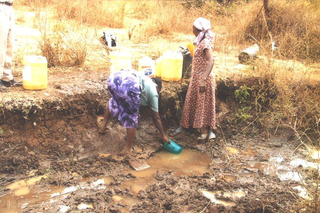 Two Women collecting dirty water before a clean alternative was provided 