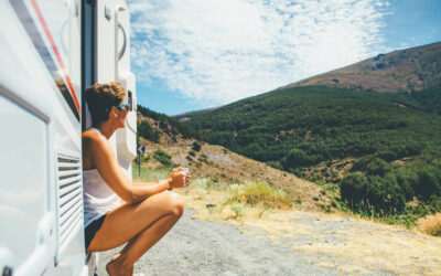 Side view of a young woman is sitting on a caravan step and holding a cup on a holiday adventure trip stop. Copy space area available