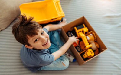 young boy smiling with box of toys